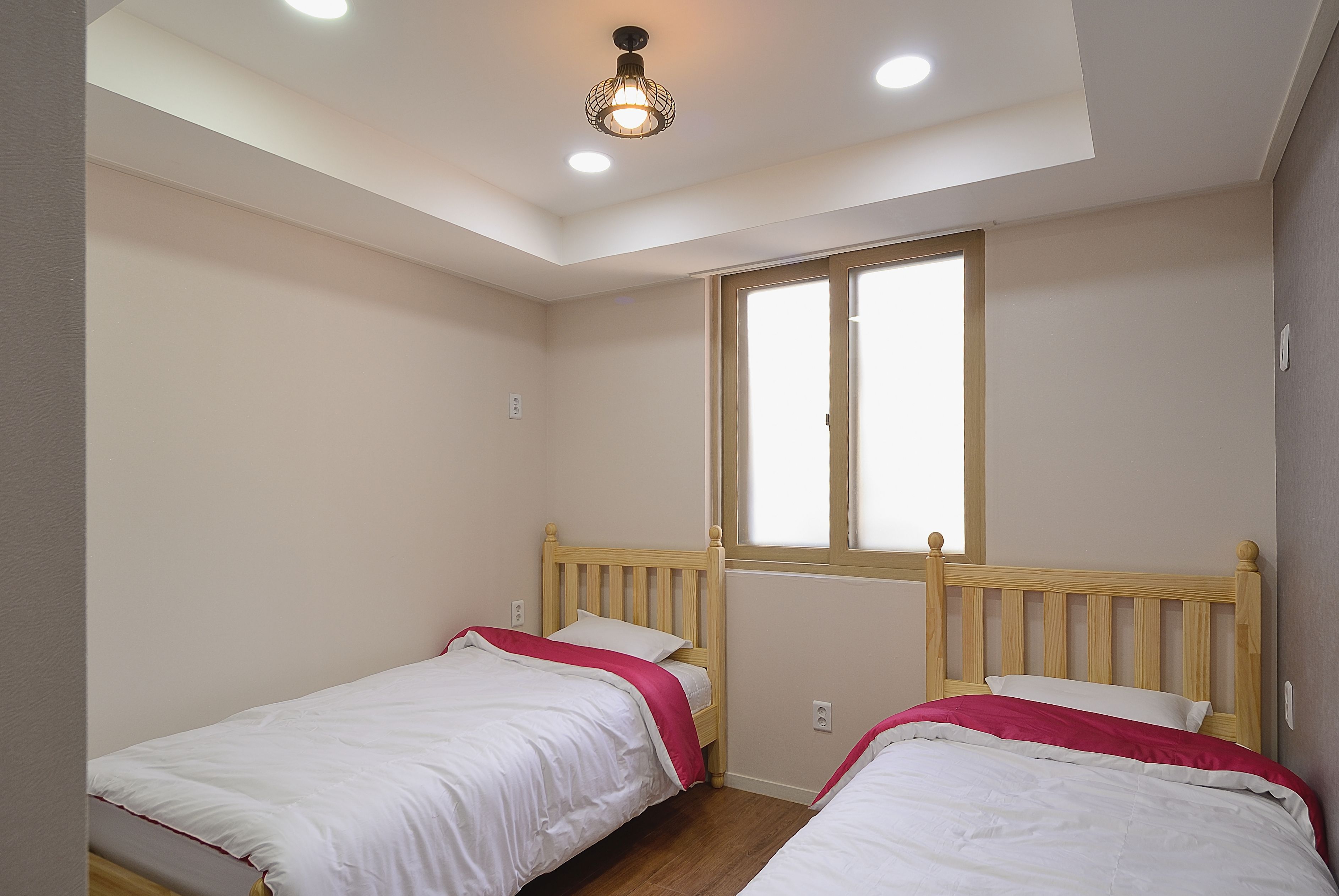 A bedroom with two single beds, a skylight, and a window.