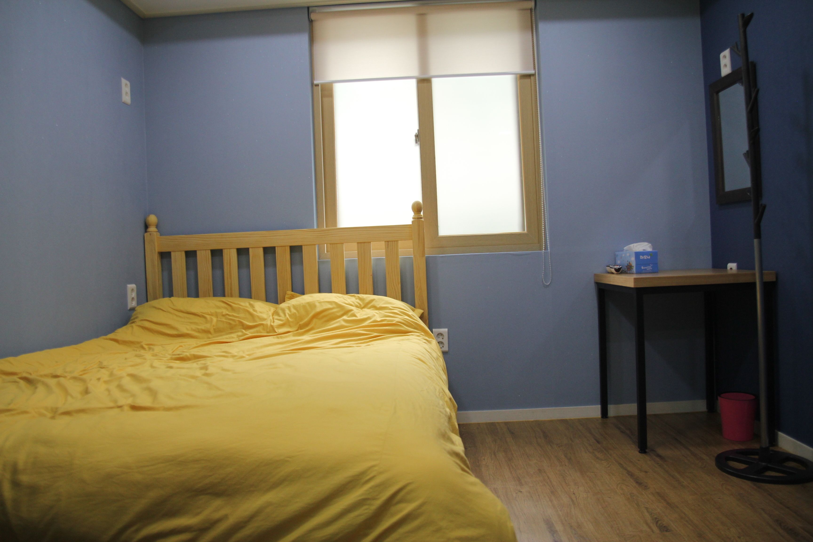 Een kamer met een bed, een raam, een tafel en een spiegel.