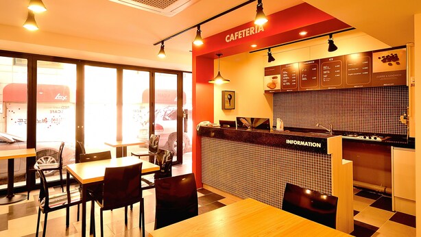 Una cafetería con mesas, sillas, un tablero de menú y una barra con un cartel que dice "CAFETERIA".