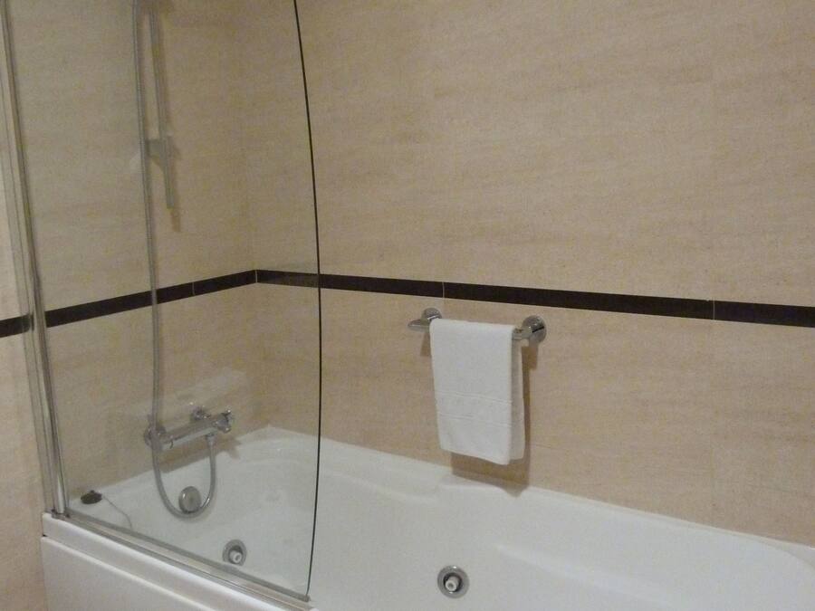 Un baño con ducha de vidrio, una bañera blanca y un inodoro.