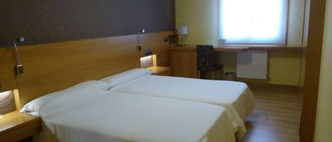 Habitación de hotel con dos camas, un escritorio y una ventana.