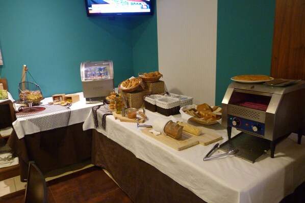 A buffet setup with various food items and a bread-making machine.