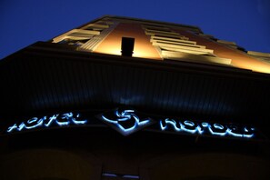 A hotel sign with illuminated letters and a geometric design above it.