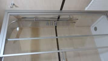 Een badkamer met een douchecabine van glas, een handdoekhouder en een toilet.
