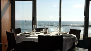 A dining table set for four with a view of the ocean and a ship in the distance.