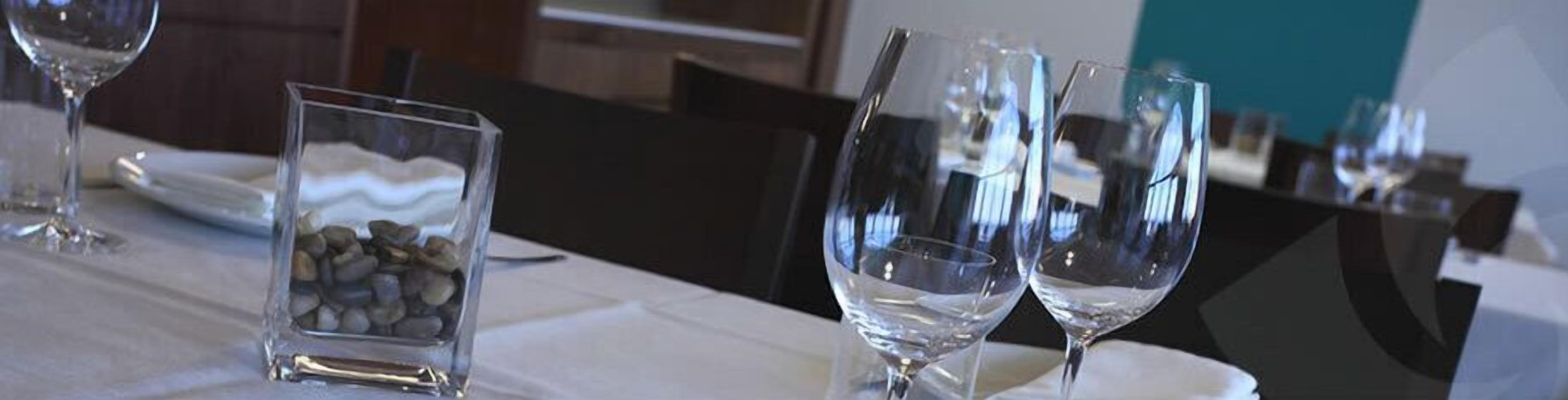 Una mesa de comedor con copas de vino y un pequeño recipiente de vidrio con piedras.