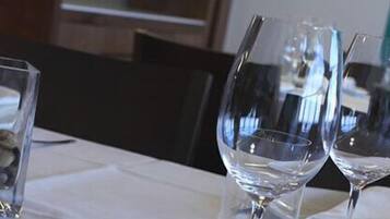 Una mesa de comedor con copas de vino y un pequeño recipiente de vidrio con piedras.