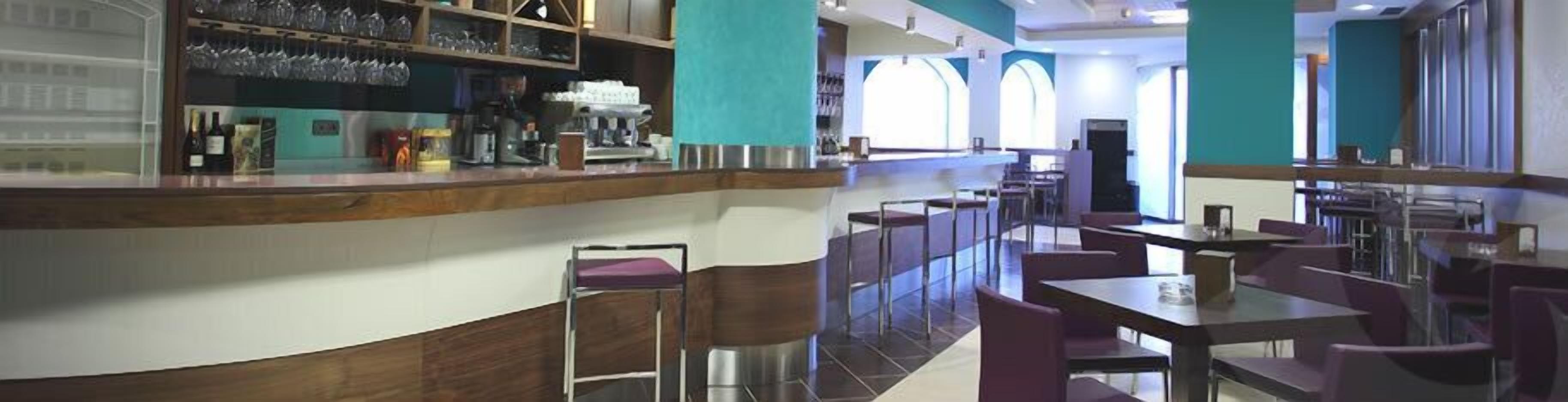 Un restaurant doté d’un bar, de tables hautes et de chaises.