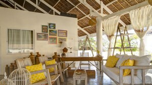 A rustic interior with wooden furniture, a dining table, and a sofa with yellow cushions. - Momo Beach House (Panglao)