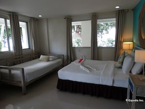 A hotel room with two beds, a wooden headboard, a swan-shaped pillow, and a lamp. - Momo Beach House (Panglao)