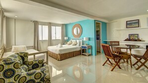 A hotel room with a bed, a desk, chairs, a mirror, and a window. - Momo Beach House (Panglao)