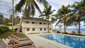 A resort with a pool, lounge chairs, and a view of the ocean. - Momo Beach House (Panglao)
