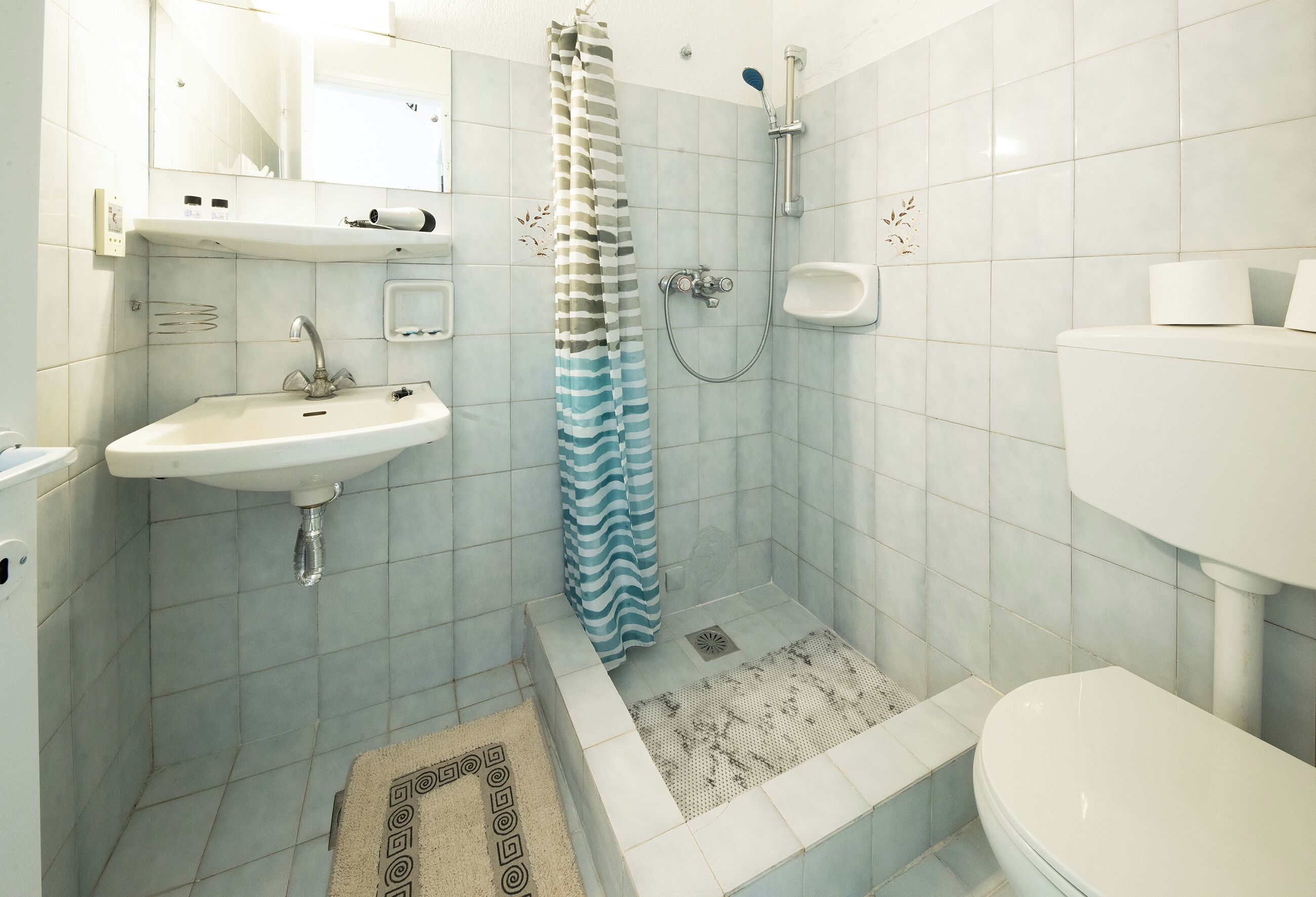 A bathroom with a sink, toilet, shower, and a towel rack.