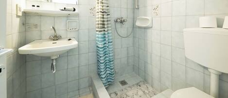 A bathroom with a sink, toilet, shower, and a towel rack.