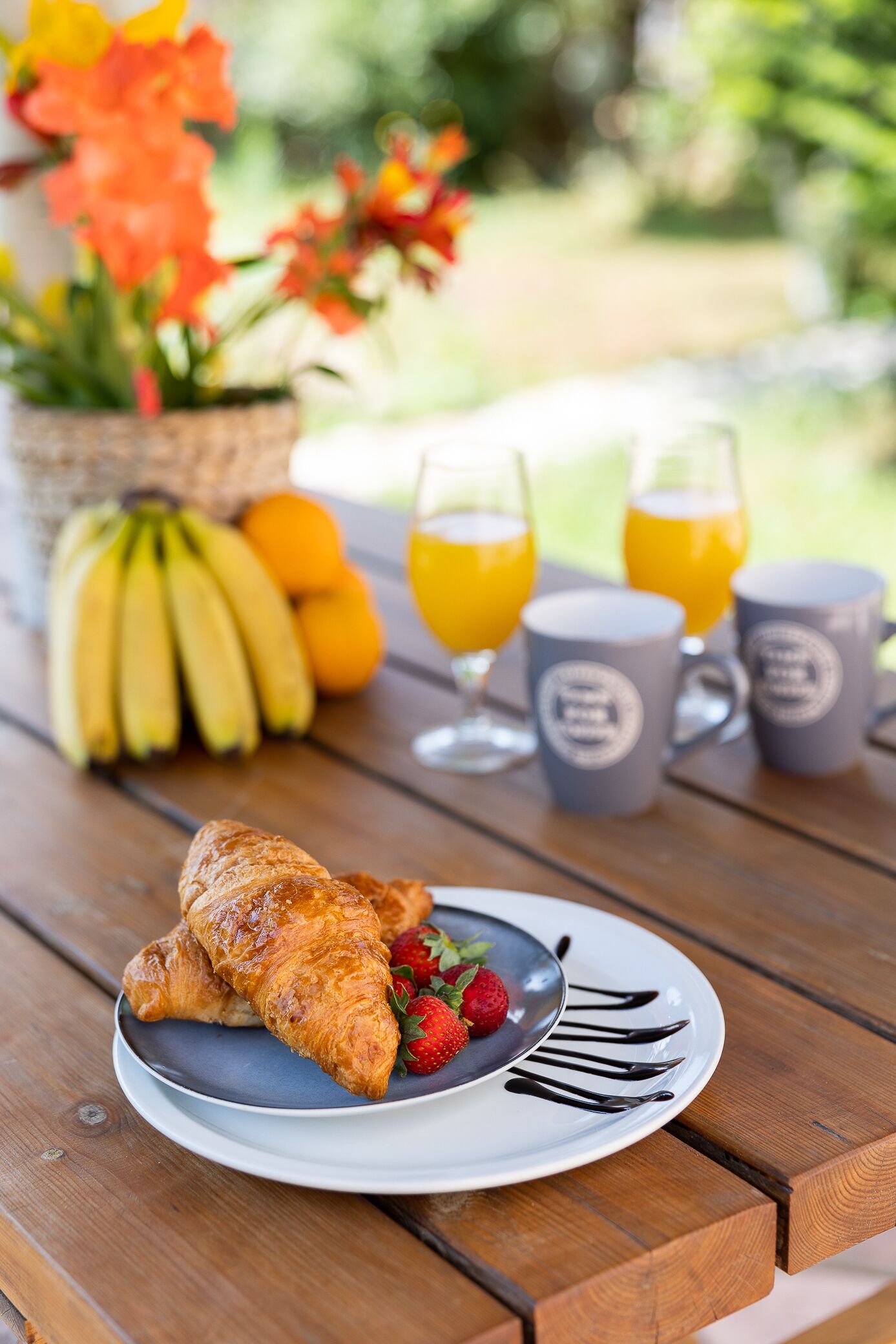 Ein Frühstücksarrangement mit Croissants, Erdbeeren und einem Teller mit Speisen auf einem Holztisch.