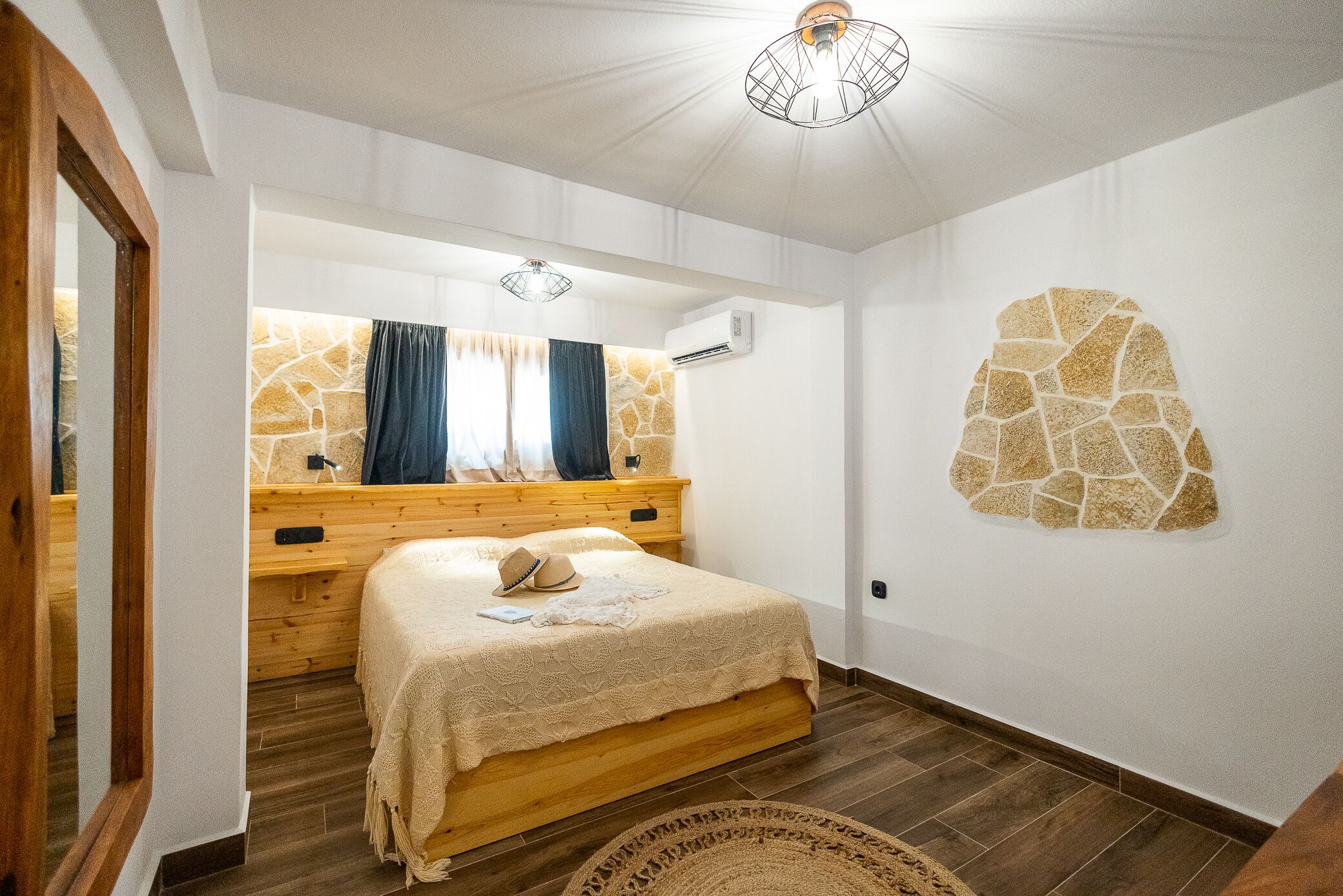 A bedroom with a wooden bed, stone wall decor, and a window with curtains.