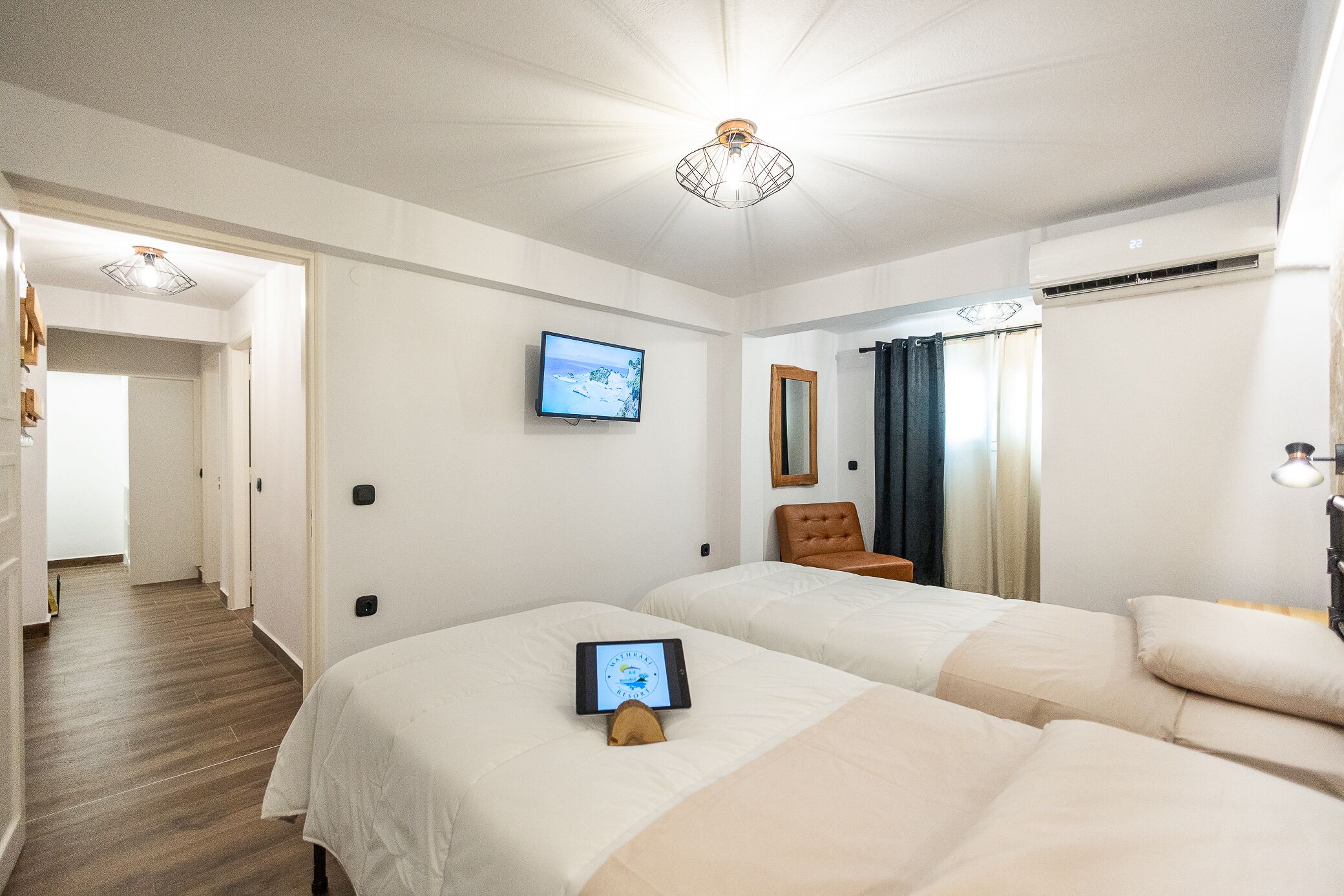 A hotel room with two beds, a television, a mirror, and a ceiling light fixture.