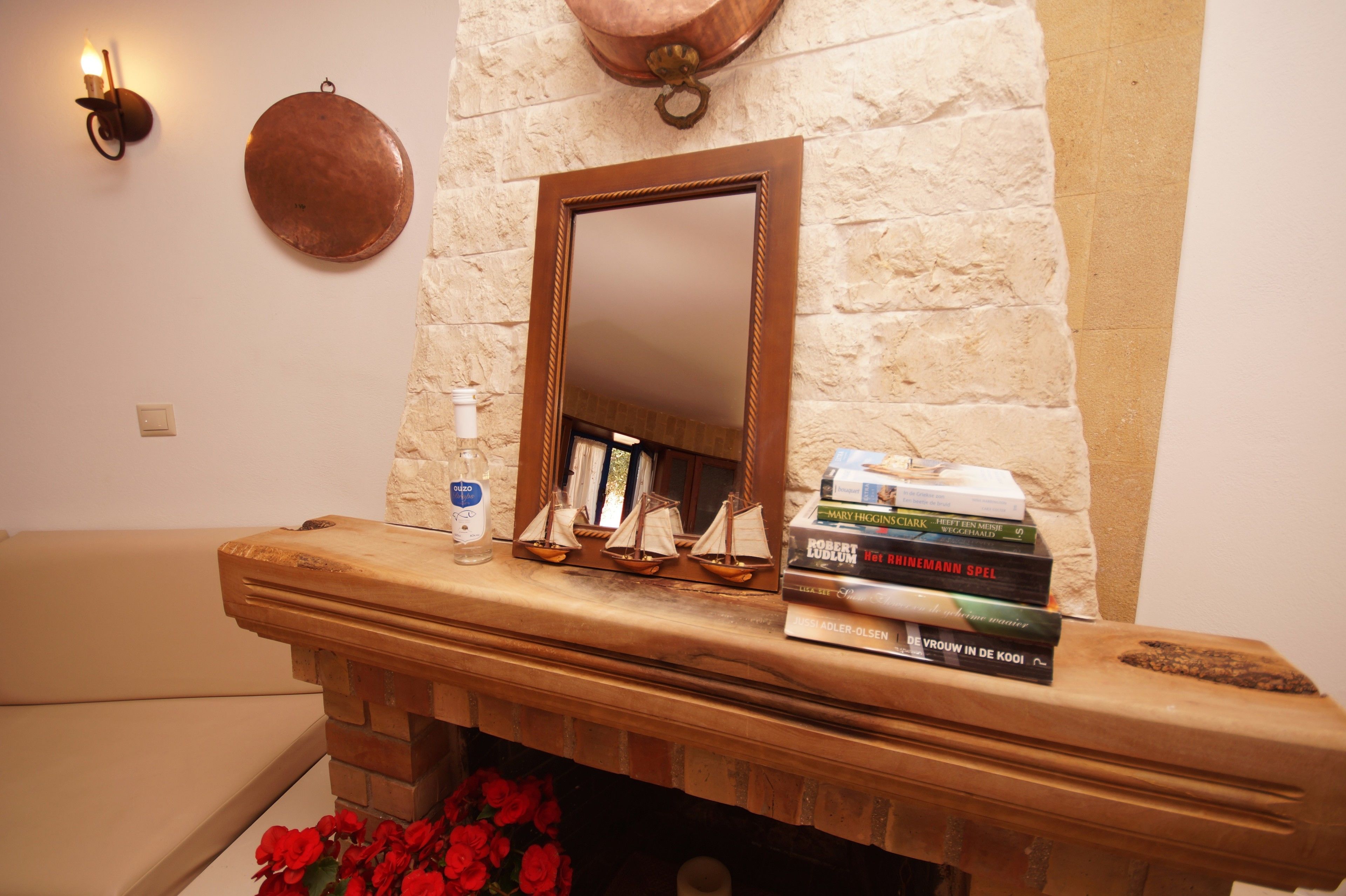 A fireplace with a mirror above it, a stack of books, and a bottle of hand sanitizer on the mantel.