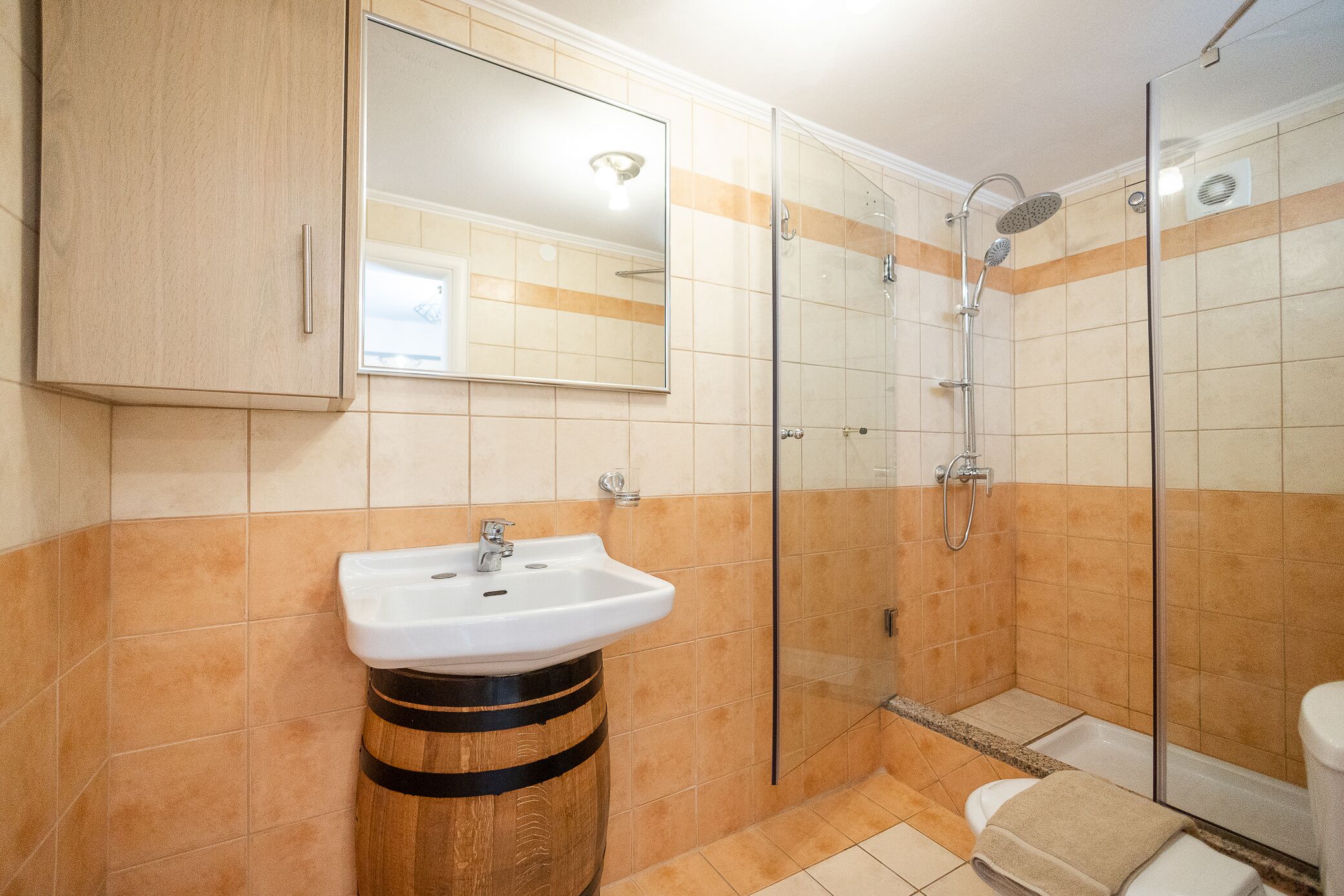 A bathroom with a wooden vanity, a sink, a glass shower enclosure, and a toilet.