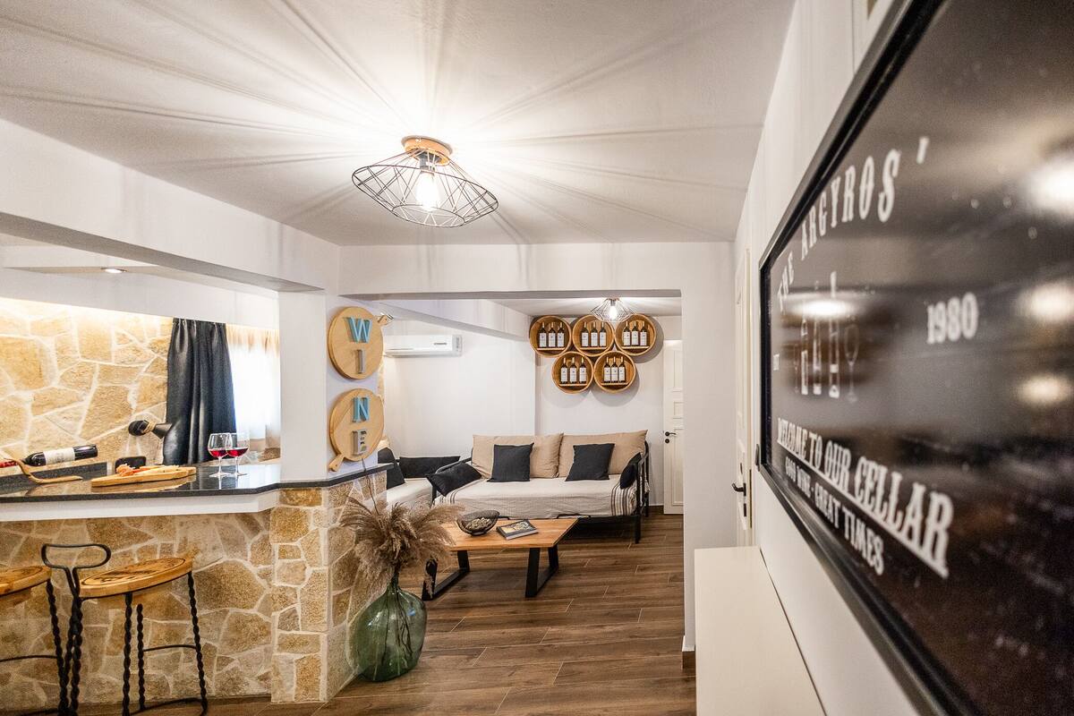 Um interior moderno com parede em pedra, área de bar e espaço de estar com sofá e mesa de centro.