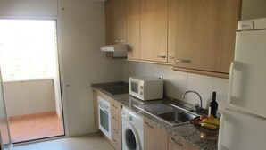 Eine Küche mit Waschmaschine, Mikrowelle, Spüle und Kühlschrank.