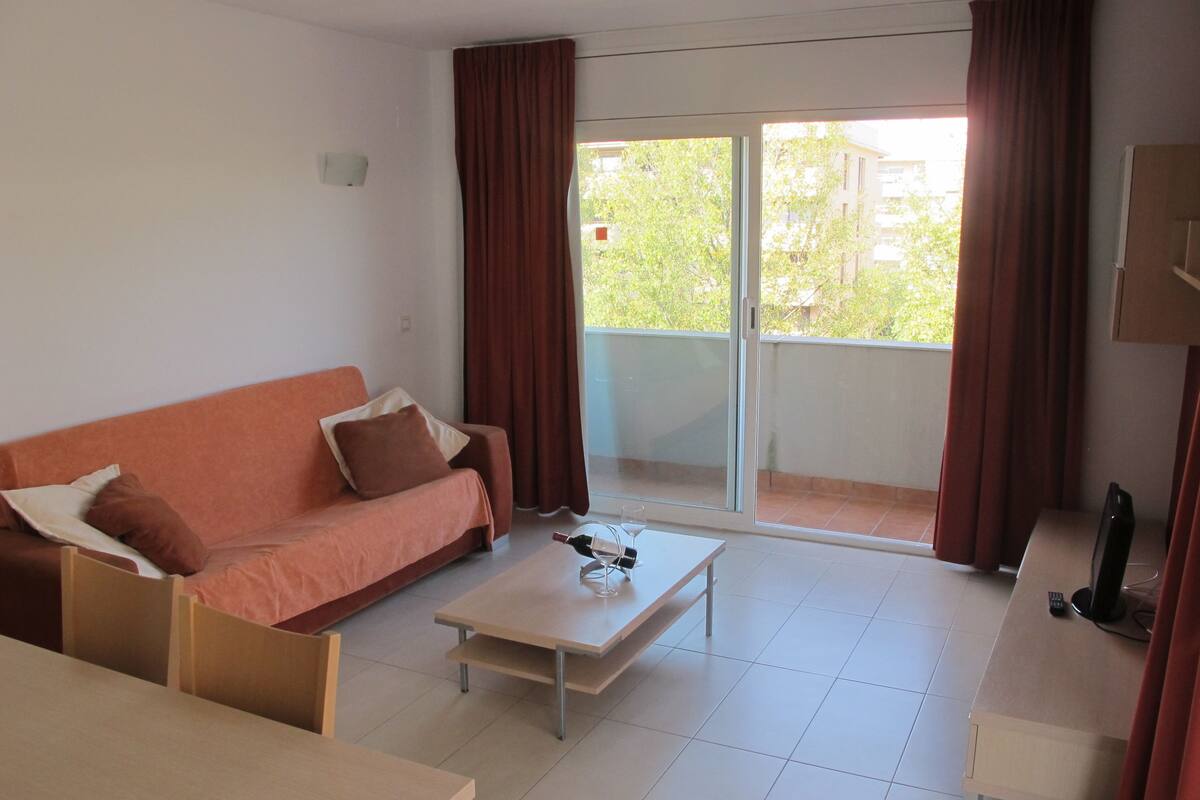 A room with a sofa, a coffee table, a TV, and a sliding glass door to the outside.