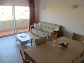 Una habitación con sofá, una mesa de comedor con sillas y una ventana con cortinas.
