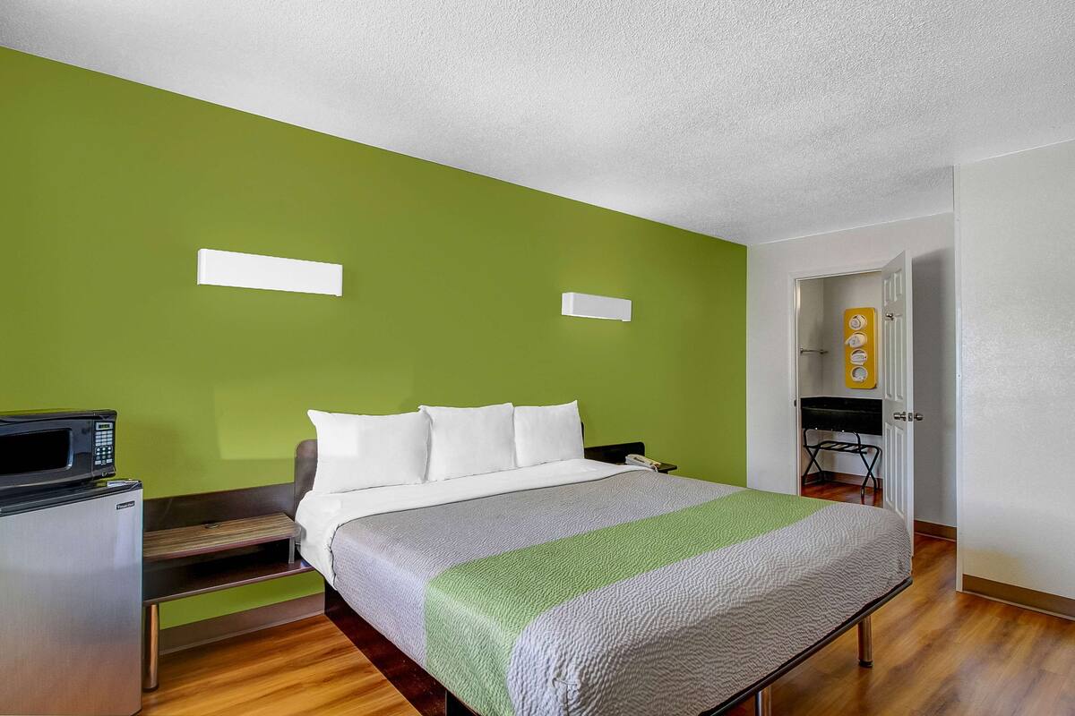 Een hotelkamer met een bed, een magnetron, een kleine koelkast en een groene wand.