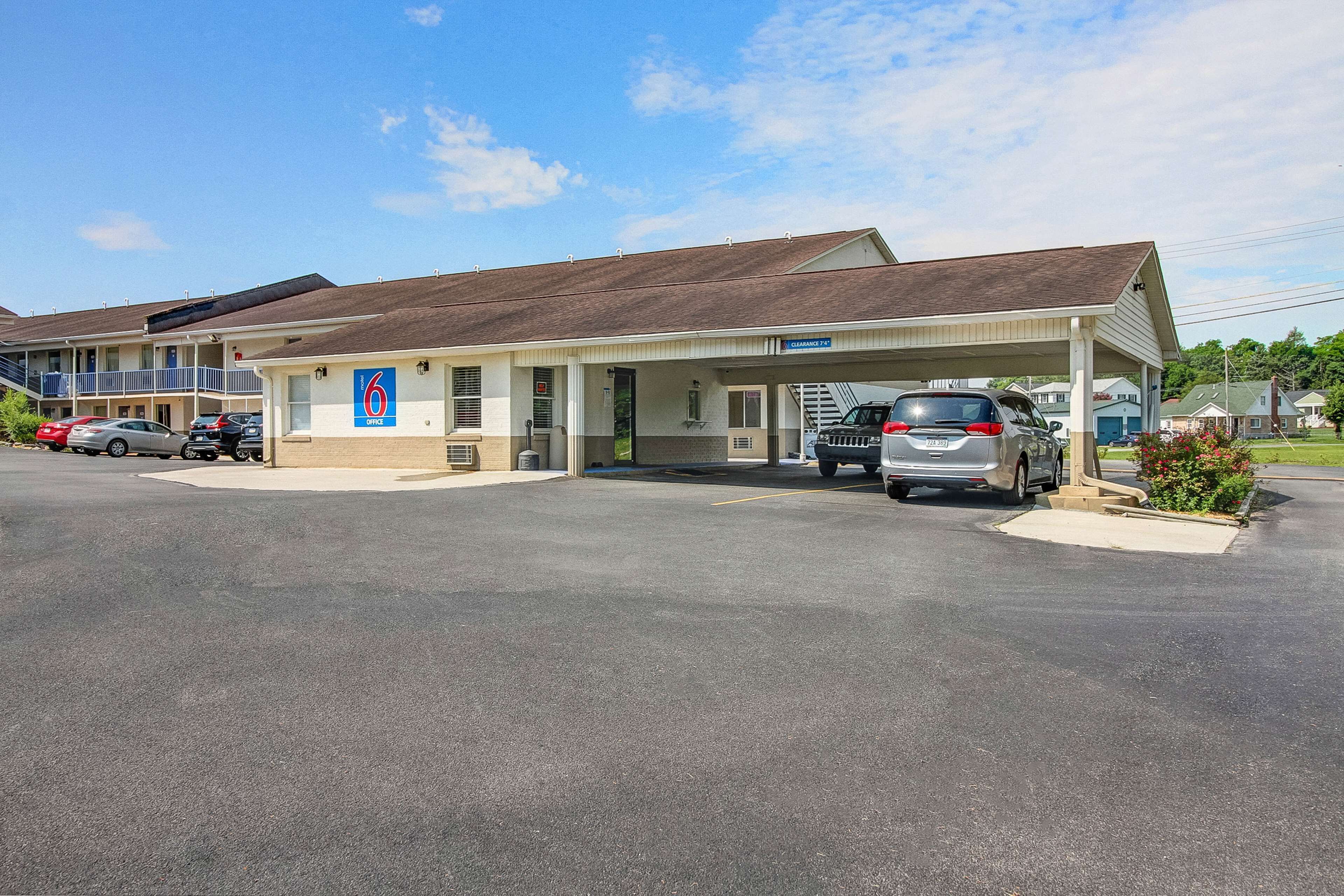 A motel with a covered parking area, multiple rooms, and a visible sign indicating the establishment name.