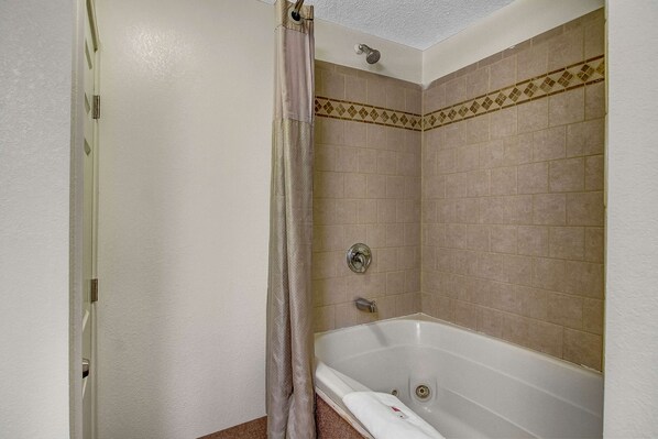 Un baño con bañera, cortina de ducha y paredes de azulejos.