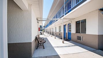 A corridor with a bench, a blue door, and a car parked in the background.