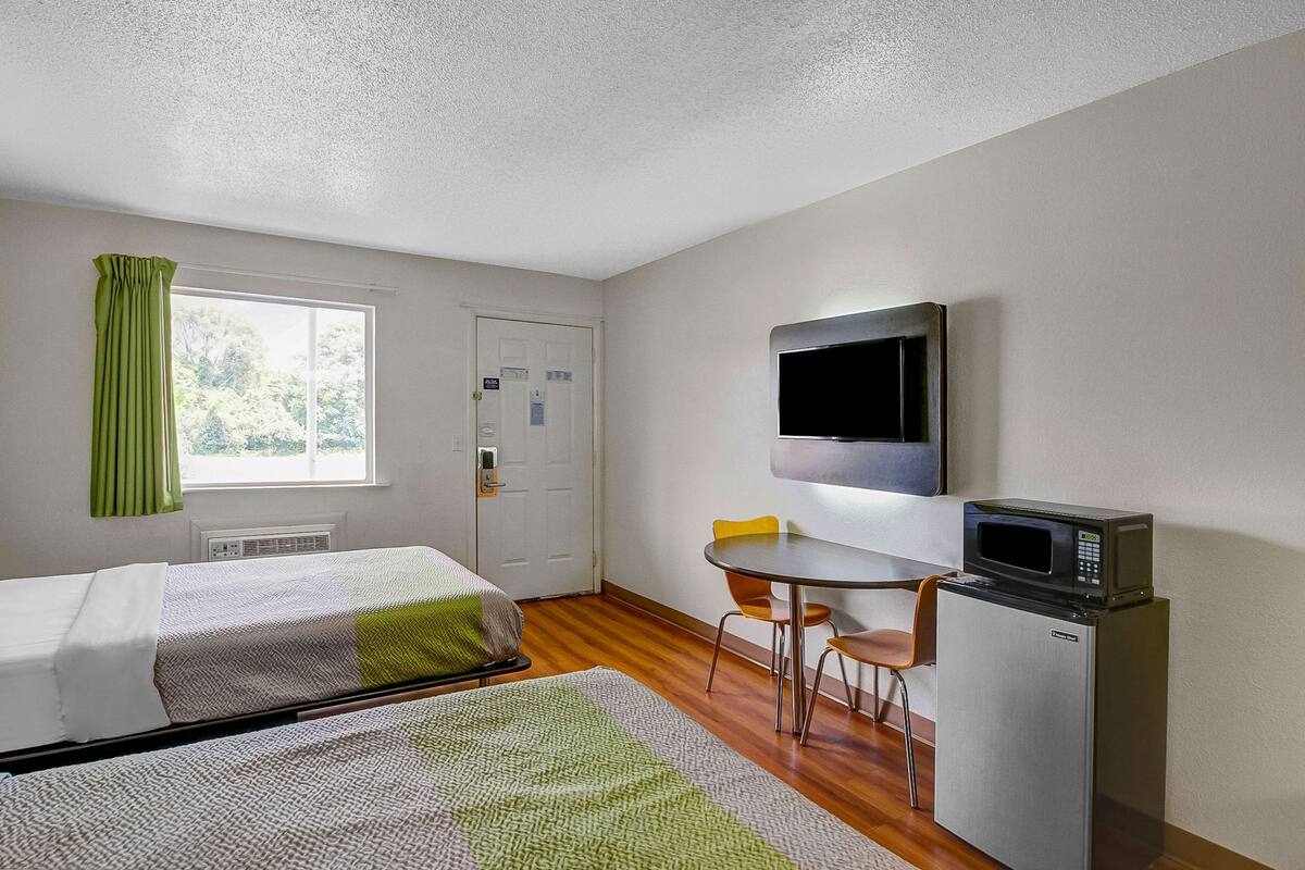 Een kamer met twee bedden, een kleine tafel, een magnetron en een televisie.
