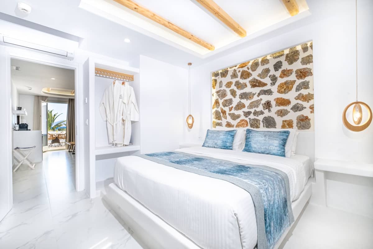 A modern bedroom with a large bed, a stone-patterned headboard, and a view of the outdoor area.