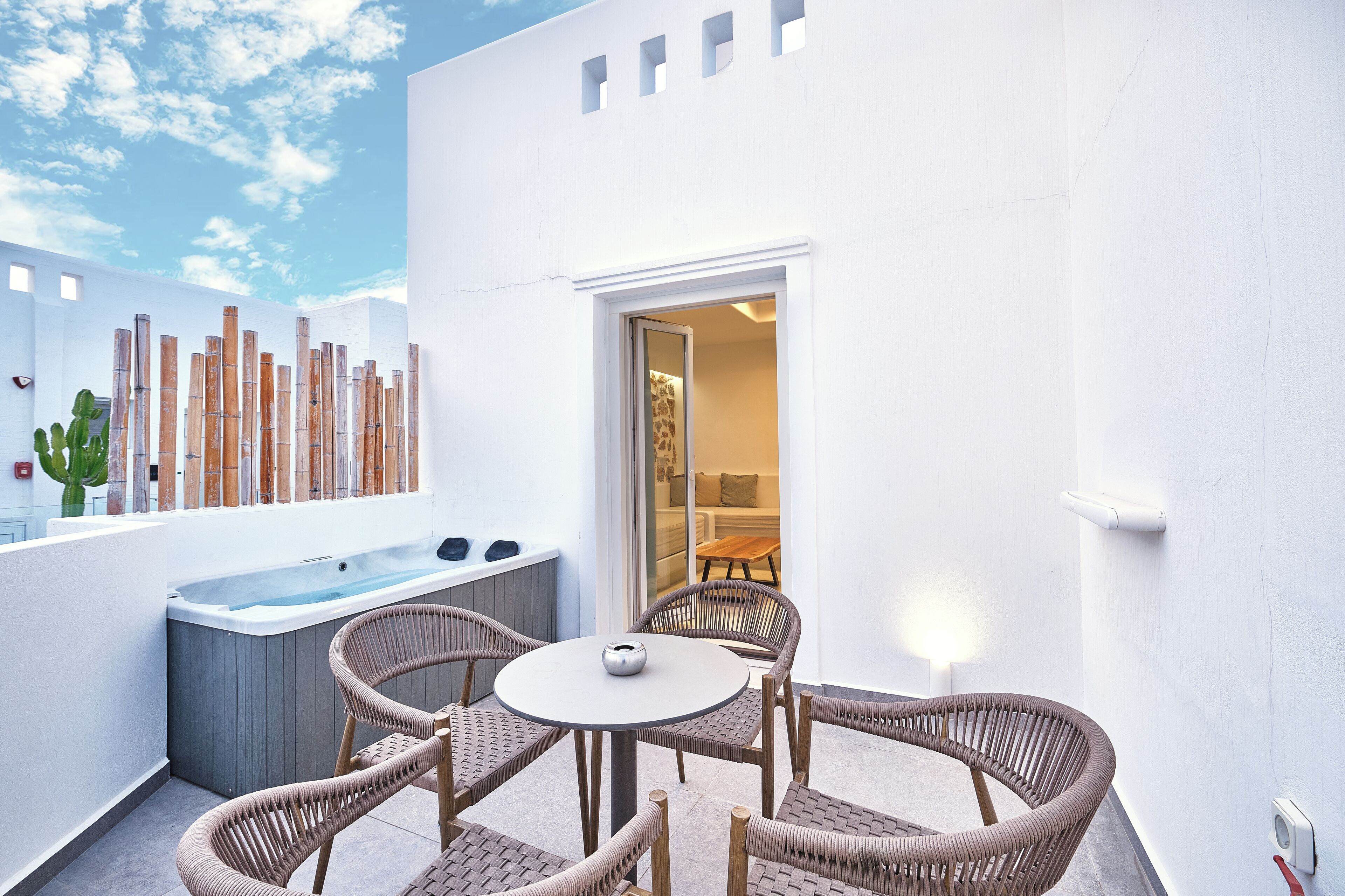 Un patio exterior moderno con un jacuzzi, sillas de mimbre y una mesa.
