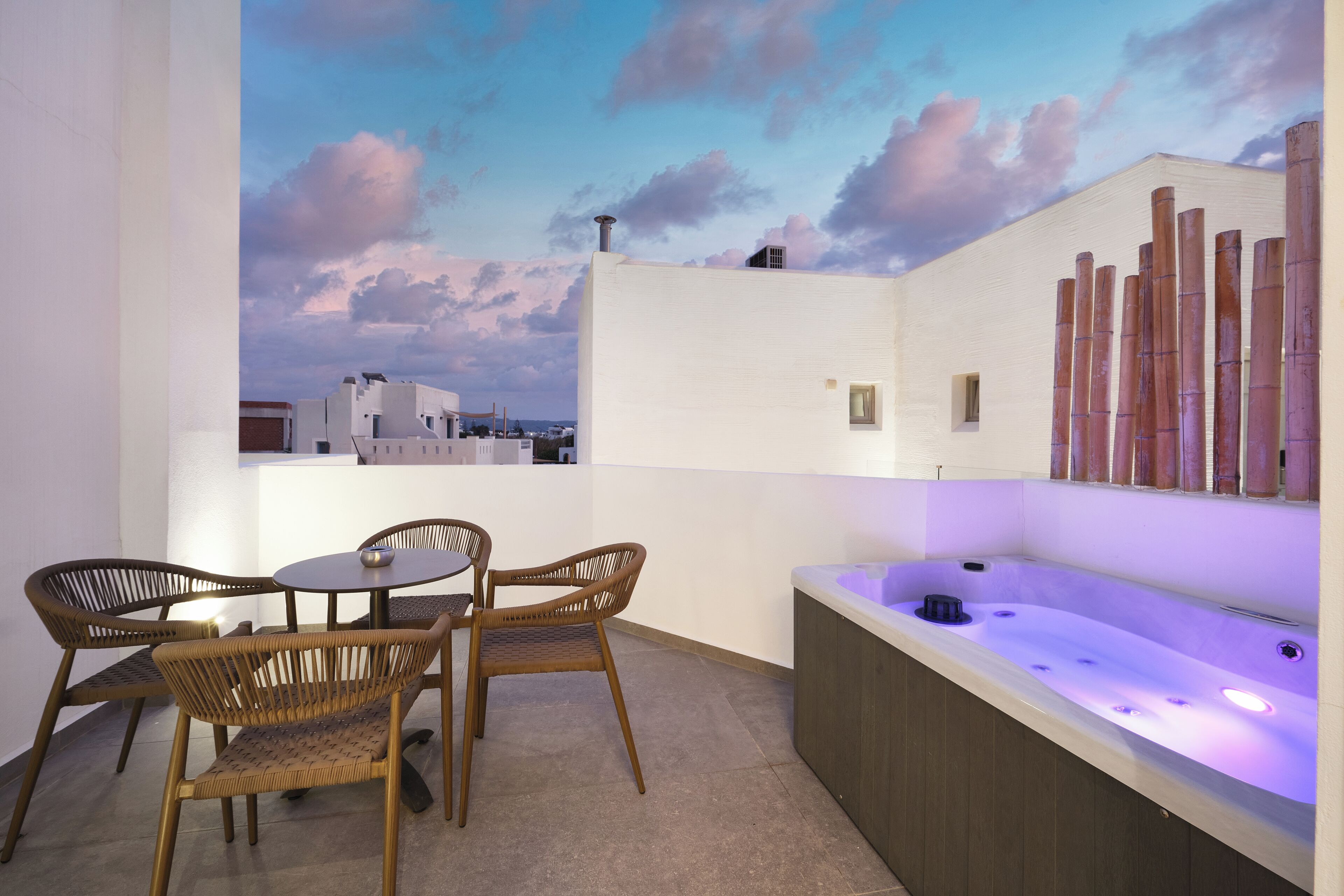 Une terrasse sur le toit avec un jacuzzi, des fauteuils en osier et une table.