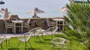 A terrace with outdoor seating, a view of the sea, and mountains in the background.
