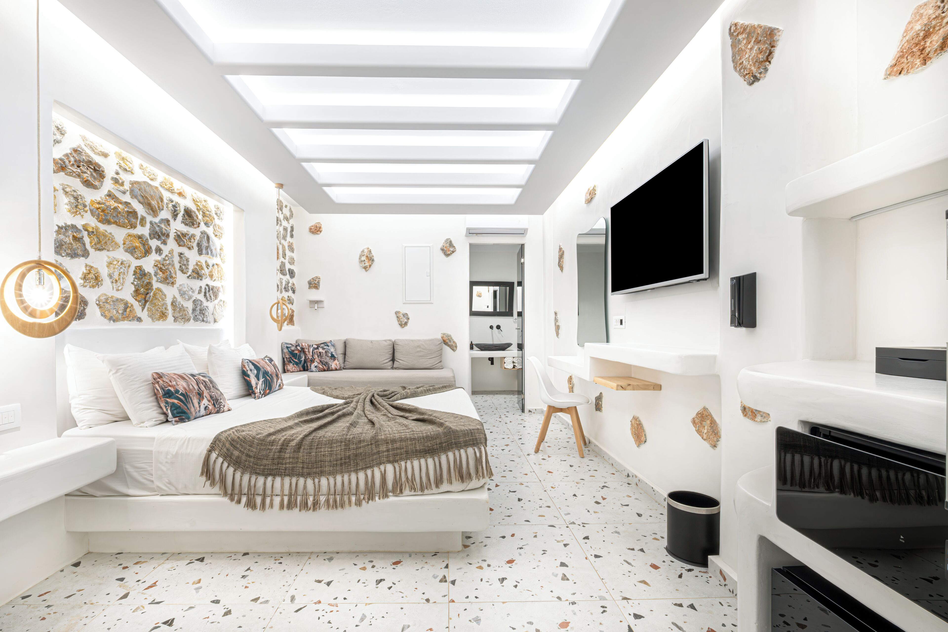 A modern bedroom with a bed, a sofa, a TV, and a piano.