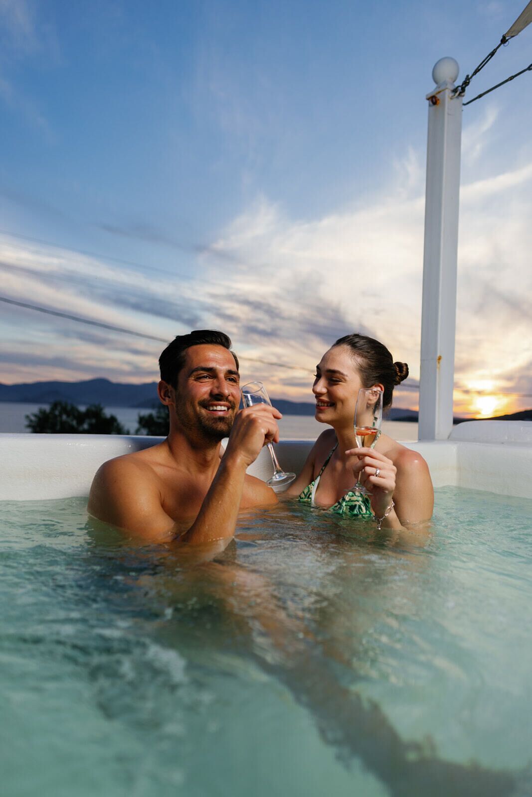 Un couple dans un jacuzzi, avec un coucher de soleil en arrière-plan.