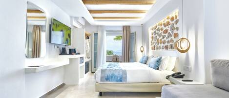 Une chambre moderne avec un grand lit, une table de chevet avec un téléphone, un bureau avec un ordinateur et un téléviseur fixé au mur.