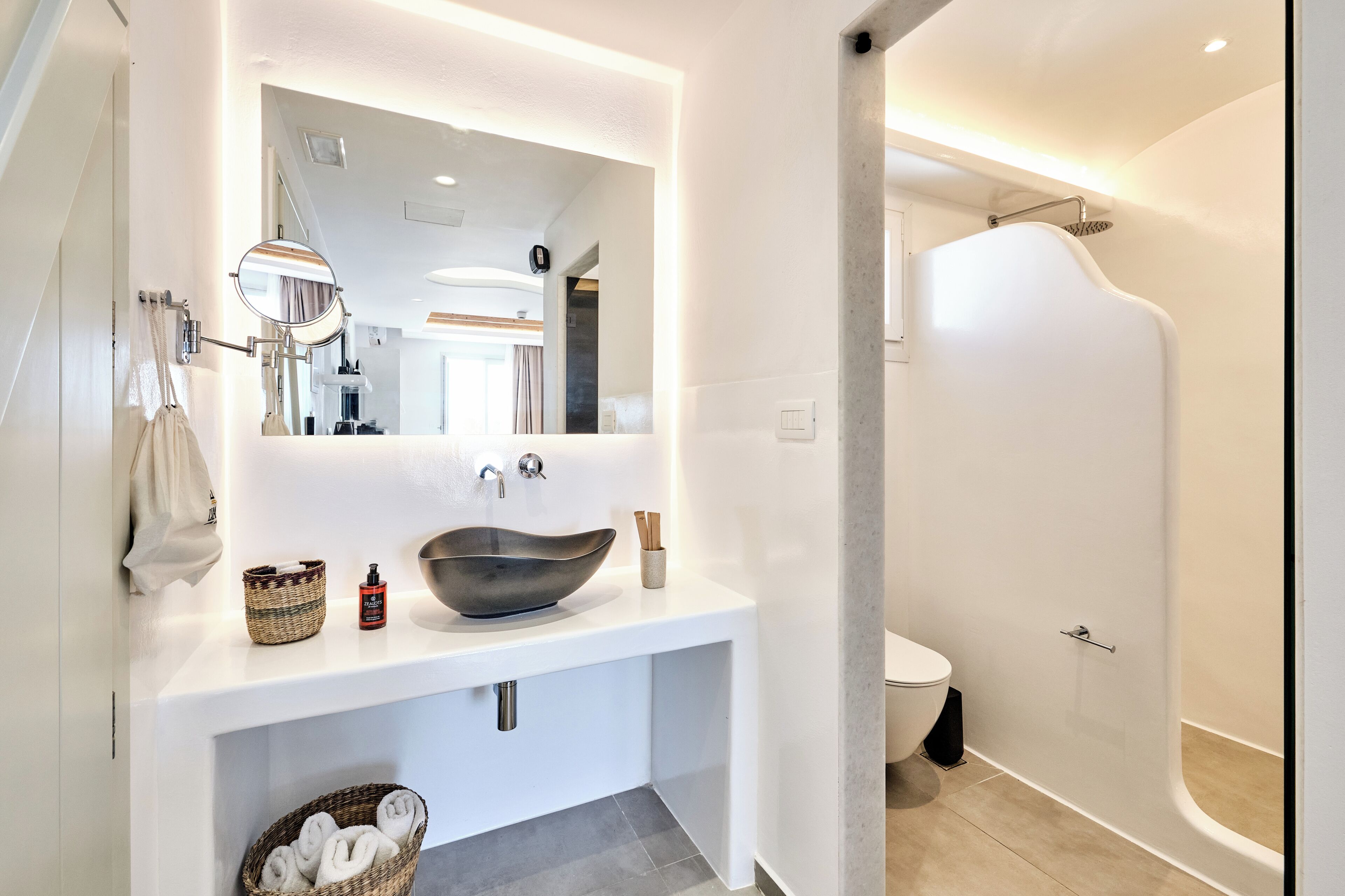A modern bathroom with a large mirror, a vessel sink, and a walk-in shower.