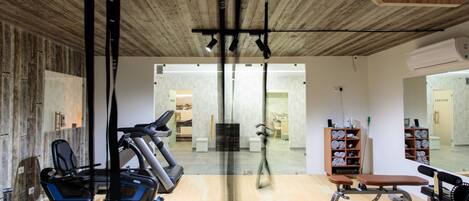 A gym with exercise equipment, a wooden floor, and a mirrored wall.