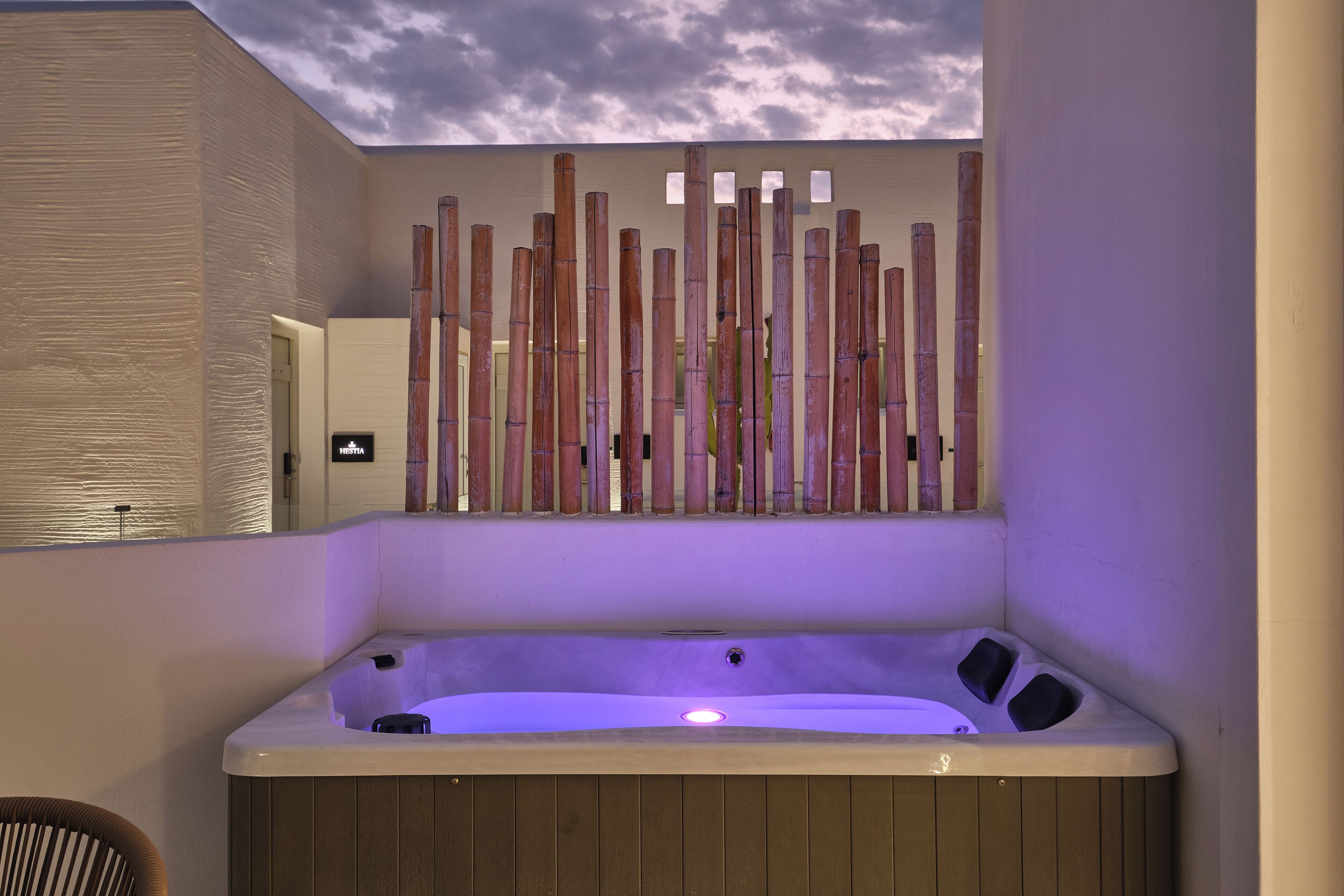 Un spa moderno con bañera de hidromasaje, paneles de madera y vistas al cielo.