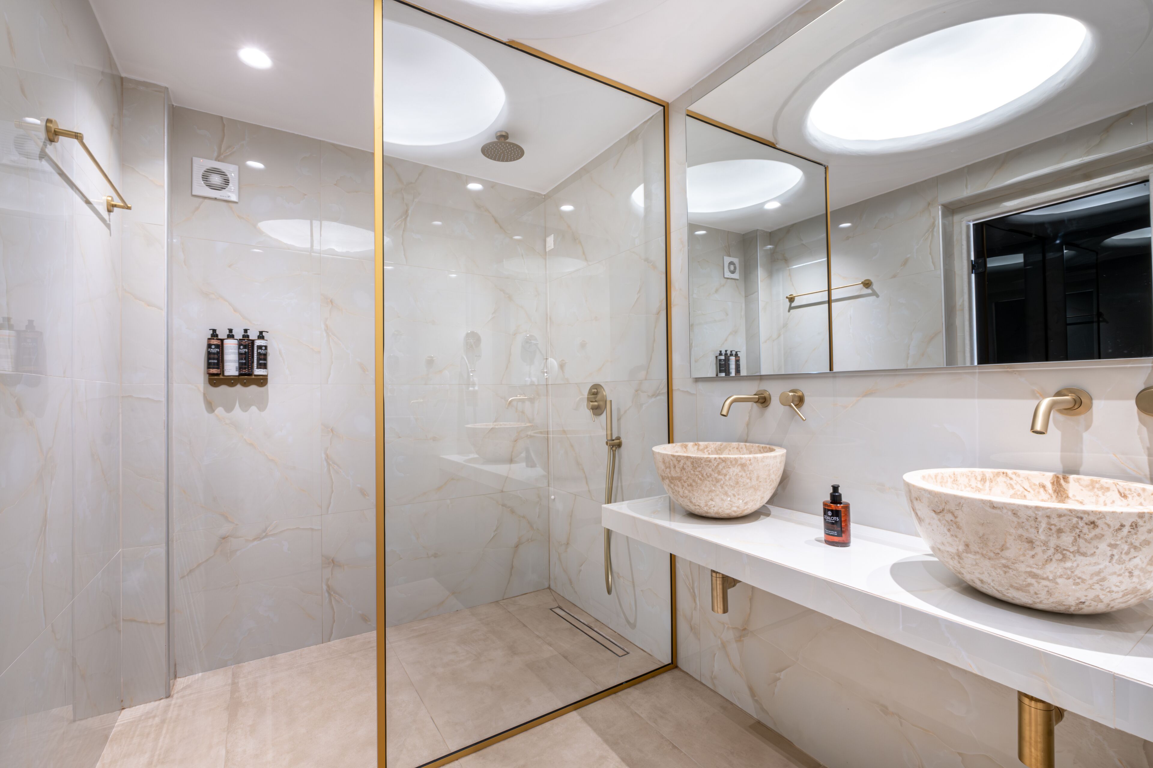 A modern bathroom with a glass-enclosed shower, two vessel sinks, and a large mirror.