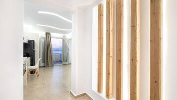 A modern hotel room with a view, a wooden accent wall, and a dining area with a chair.