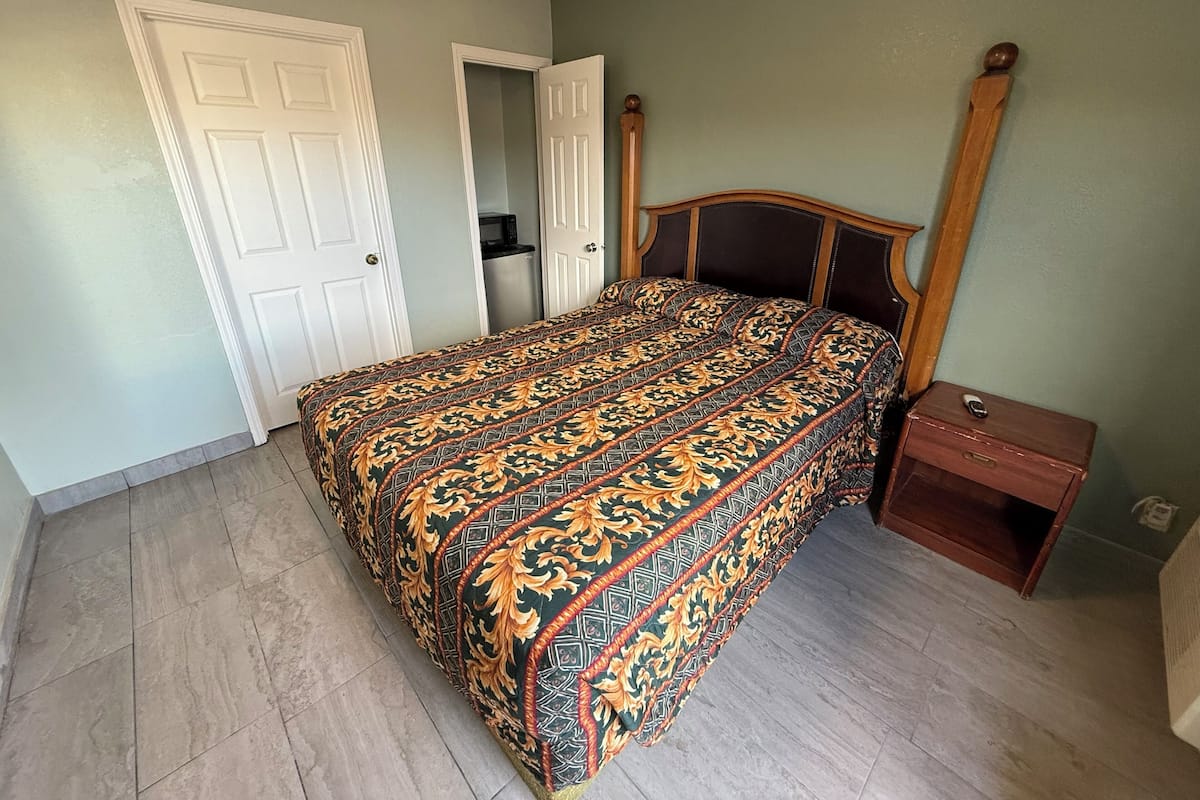 A bedroom with a bed, a nightstand, a wardrobe, and a door.