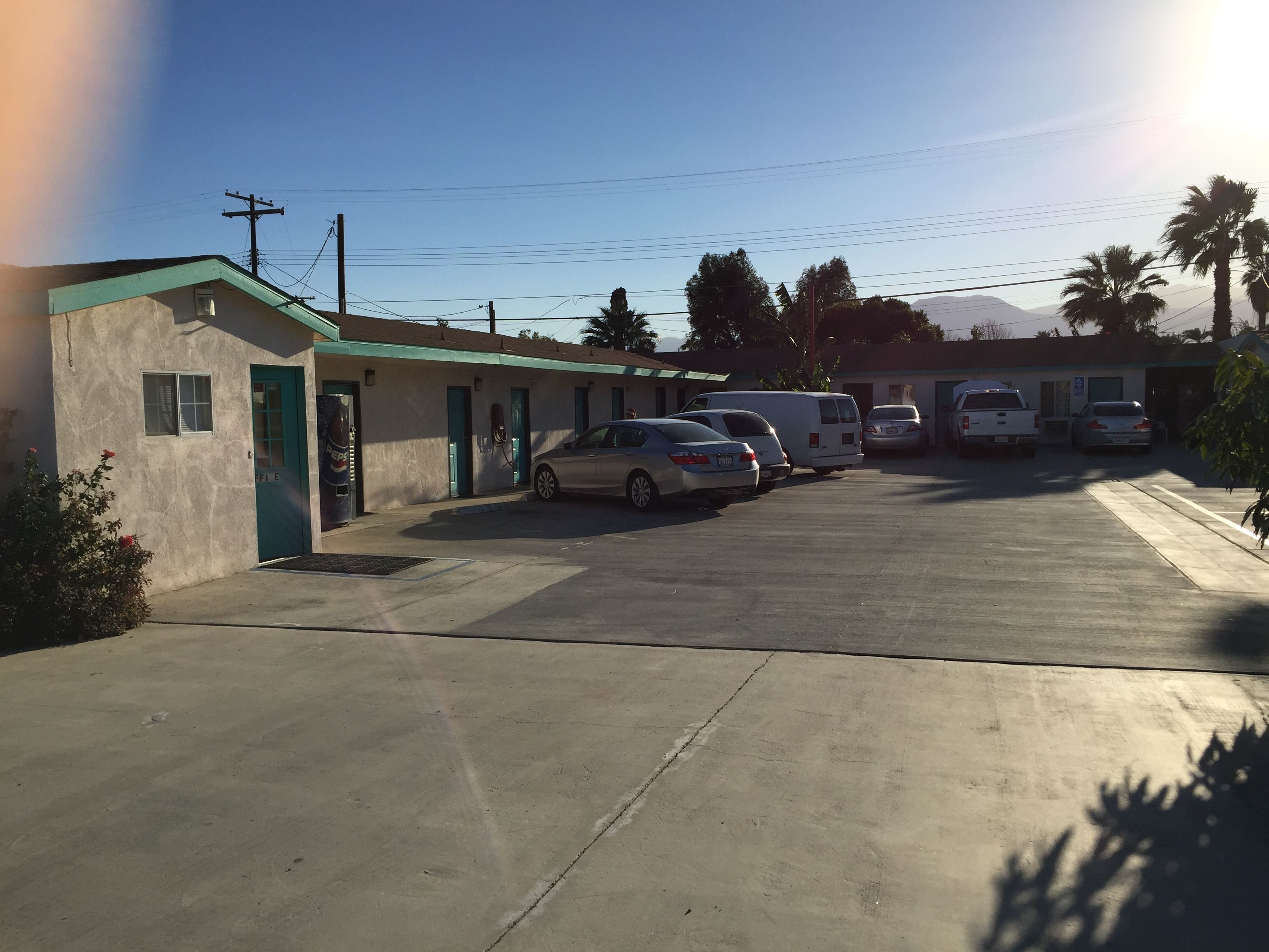A parking lot with several cars and a building with a green roof.