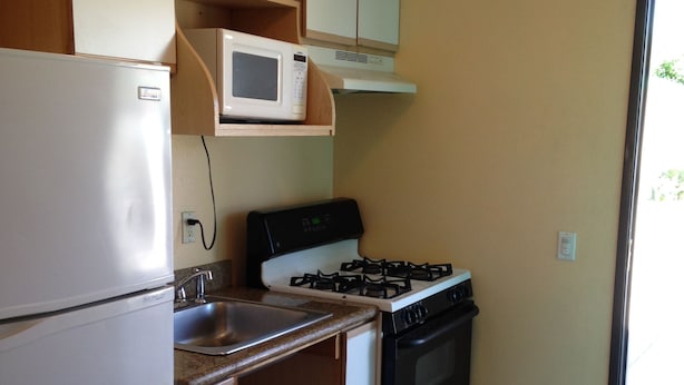 Una cocina compacta equipada con refrigerador, estufa, microondas y pileta.