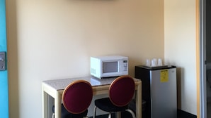 Una pequeña kitchenette equipada con microondas, refrigerador y dos sillas.