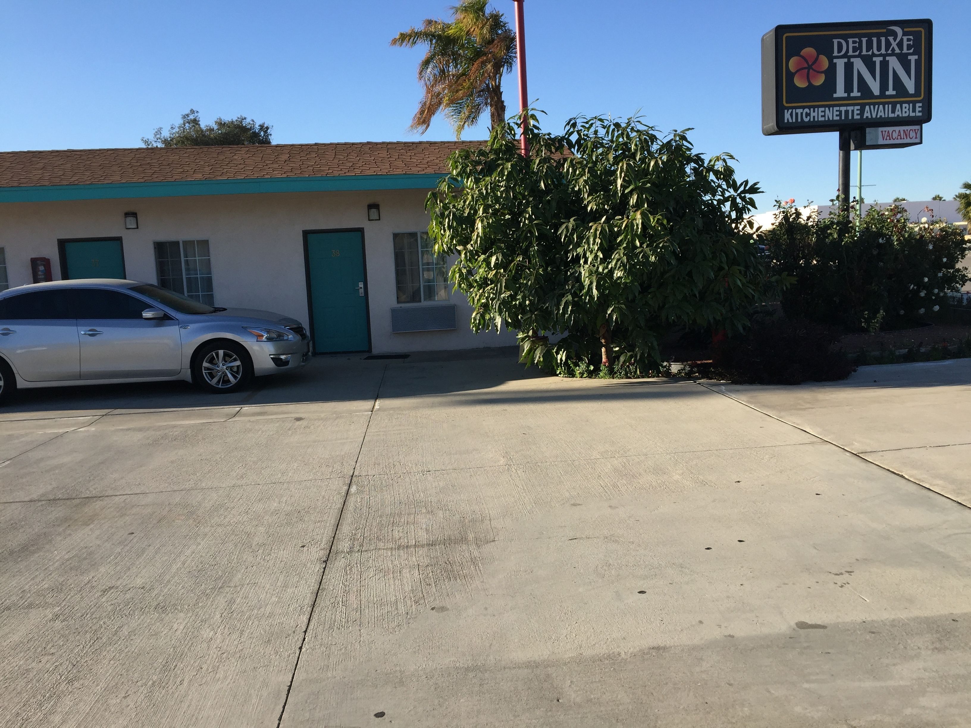 A building with a sign for 'Deluxe Inn' and a 'Kitchenette Available' notice. A car is parked in front.