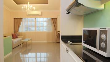 A compact living space with a kitchenette, a sofa, a coffee table, and a window with curtains.